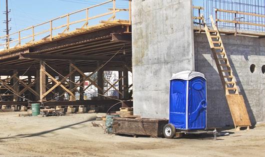 blue porta potties arranged in a neat line on a construction site